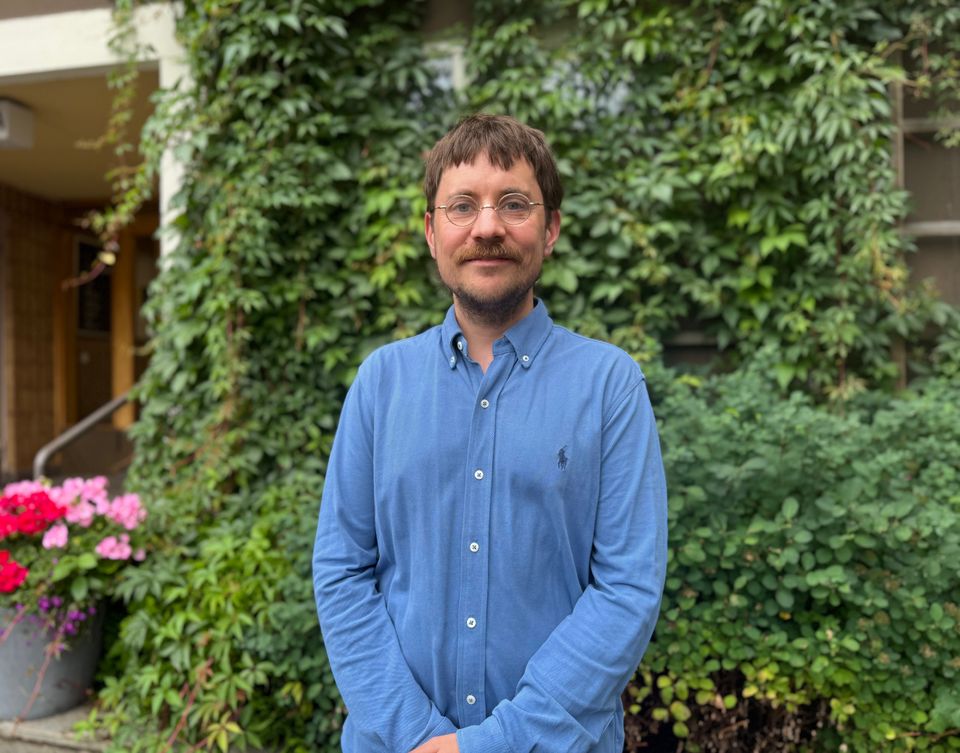 Väitöskirjatutkija Henrik Sjöblom seisoo vehreän seinän edessä.